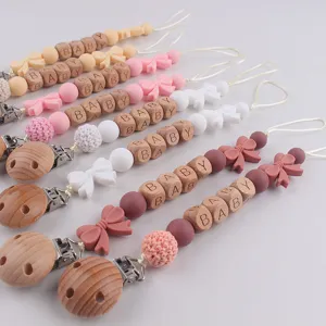 Handmade baby pacifier clips with wooden letter beads and silicone teething toys for infants.