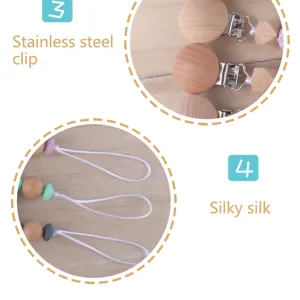 Wooden baby pacifier clip detail view with stainless steel hardware and secure cord.