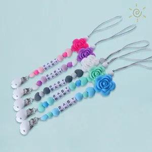 Detalle clip chupete silicona, cuentas de rosa, cuentas de letras, pinza de metal.
