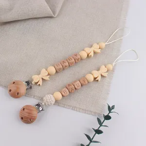 Silicone and wooden pacifier clip detail with cute bow beads and engraved baby blocks.