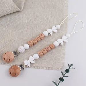 Close-up detail of wooden silicone baby pacifier clip featuring cute bow beads and secure clip.