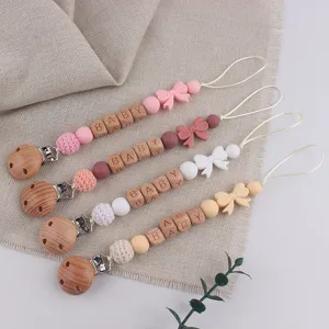 Detailed close-up of cute baby pacifier clips with silicone beads and wooden alphabet blocks.