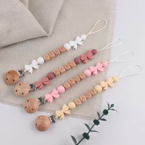 Wooden and silicone baby pacifier clip detail showing cute bow charms and safe wooden beads.