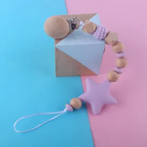 Close-up of wooden and silicone baby pacifier clip with star teether and beads detail.