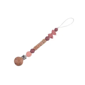 Cute wooden silicone baby pacifier clip with beads and bow for teething infants and toddlers.