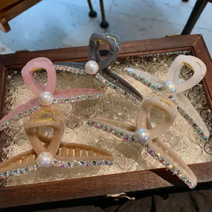Gros plan de grandes pinces à cheveux en résine avec strass étincelants et perle élégante.