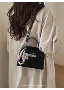 Stylish black crocodile pattern shoulder bag with knit flower pendant for women detail.