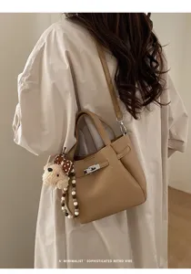 Detailed shot of retro commuter shoulder bag with cute bear charm and metal turn-lock clasp.