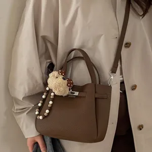 Chic brown leather shoulder bag with cute plush bear charm, stylish casual crossbody design.