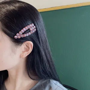 Vista dettagliata di una forcina con strass rosa brillante su capelli scuri, accessorio.