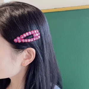 Primo piano dettagliato di un elegante fermaglio BB in strass rosa indossato sui capelli scuri.