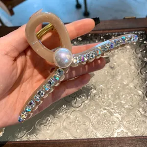 Vue détaillée d'une pince à cheveux beige de style coréen avec strass et grande perle.