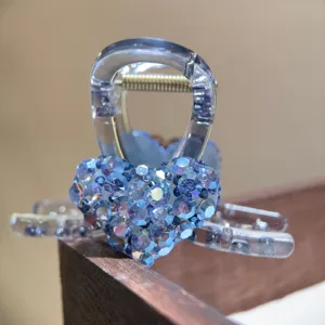 Blue rhinestone heart hair claw detail, transparent acrylic hair clip for women close up.