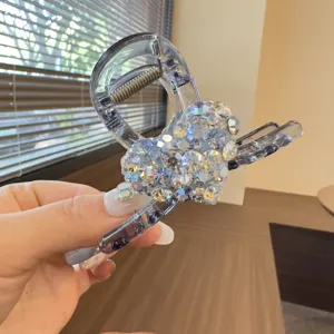 Detail view of a sparkling crystal heart hair claw clip, elegant clear resin shark clip for women.