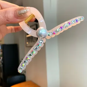 Gros plan sur la pince à cheveux rose en résine avec des strass étincelants et une perle.