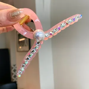 Vue de detail d'une pince a cheveux en acrylique rose avec strass et perle pour coiffure.