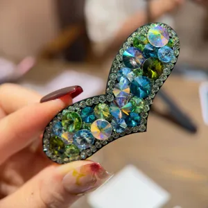 Pince à cheveux étincelante en cristal gros plan, détail de barrette latérale en strass vert et bleu.