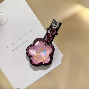 Gros plan détaillé de la jolie pince à cheveux fleur en cristal avec des strass rose brillants.