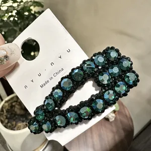 Dettaglio di un fermaglio BB con strass verdi scintillanti su cartoncino, accessorio capelli chic