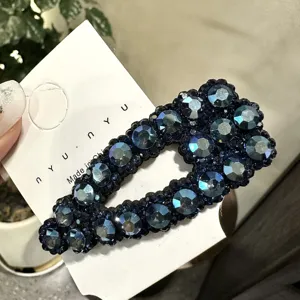 Dettaglio molletta per capelli con strass blu scuro, cristalli brillanti, accessorio chic.