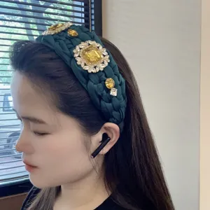 Primer plano de una diadema trenzada verde oscura decorada con estrases amarillos brillantes.