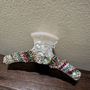 Nahaufnahme der funkelnden Strass-Haarklammer mit bunten Kristallen und eleganter Schleife.