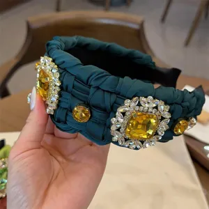 Diadema trenzada verde oscura con grandes pedrerías de color ámbar, accesorio elegante.