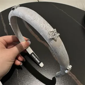 Detailaufnahme eines chinesischen, bestickten Satinhaarreifs mit Kristallsternen.
