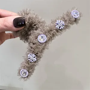 Detalle en primer plano de la pinza de tul champán con botones de pedrería y estrás.