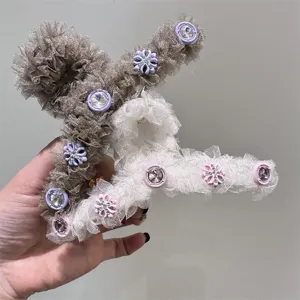 Detalle de pinza de pelo esponjosa de malla con volantes y botones de cristal.