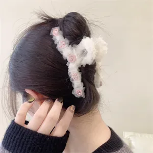 Detalle en primer plano de la pinza de pelo de tul blanco esponjoso con botones florales.