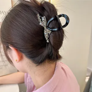 Gros plan detail de pince a cheveux noire avec noeud en strass pour coiffure elegante femme.