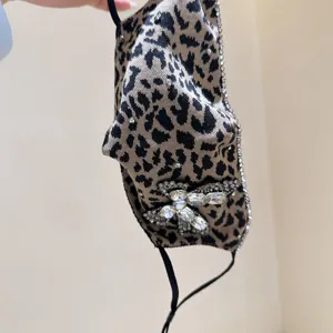 Leopard print face mask with sparkling rhinestones and crystal butterfly detail, chic accessory.