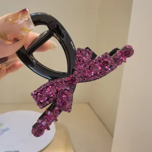 Gros plan d'une pince à cheveux noire élégante décorée de strass violets brillants.