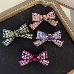 Détail de pince à cheveux nœud en strass avec design en cristal étincelant en couleurs.