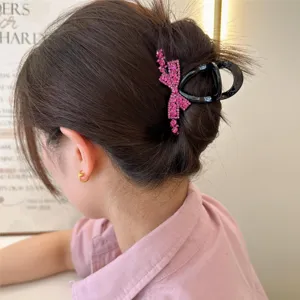 Vue détaillée d'une élégante pince à cheveux noire décorée d'un nœud en strass roses brillants.