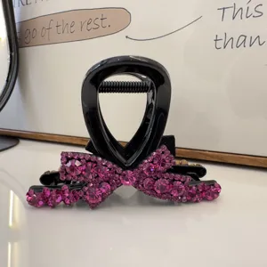 Détail en gros plan d'une pince à cheveux noire décorée de strass roses scintillants.