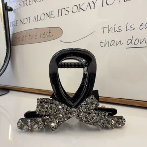 Vue détaillée d'une pince à cheveux nœud en strass noir, accessoire élégant pour femmes.