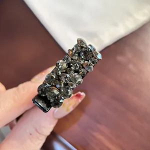 Gros plan détaillé d'une pince à cheveux étincelante en strass sombres, style élégant.
