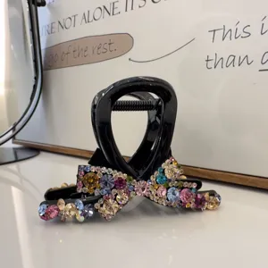 Vue détaillée de la pince à cheveux noire ornée de strass colorés brillants en forme de nœud.