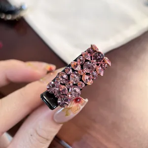 Gros plan détail d'une petite pince à cheveux bec de canard en strass roses brillants.