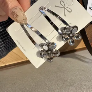 Pinces à cheveux clic-clac en métal argenté avec fleurs en cristal gris étincelantes.