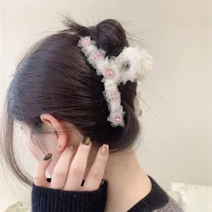 Detalle en primer plano de pinza de pelo de malla blanca con flores de estrás rosa dulce.