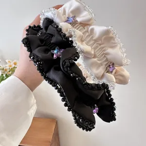 Nahaufnahme des plissierten Stoffhaarreifs mit Kristallperlen und lila Stern-Strass.