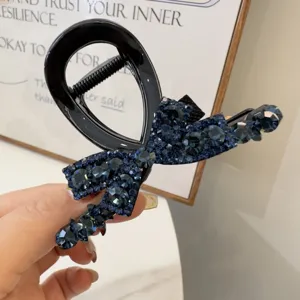 Gros plan d'une pince à cheveux noire décorée de strass bleu foncé scintillants en forme de nœud.