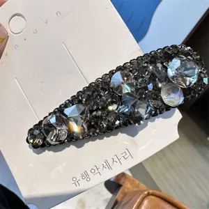 Détail de pince à cheveux goutte de cristal étincelante, élégante épingle strass noire.