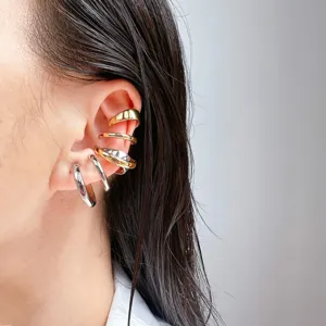 Detail shot of multi-layer metallic C-shaped ear cuffs, stylish stacked non-pierced ear jewelry.