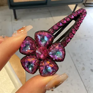 Gros plan détaillé de la pince à cheveux fleur en strass rose, détails de cristaux étincelants.