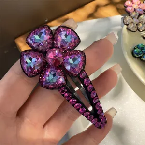 Gros plan détaillé d'une pince à cheveux fleur en cristal violet avec strass brillants.