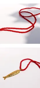 Exquisite close-up of the golden fish pendant and vibrant red seed bead chain details.